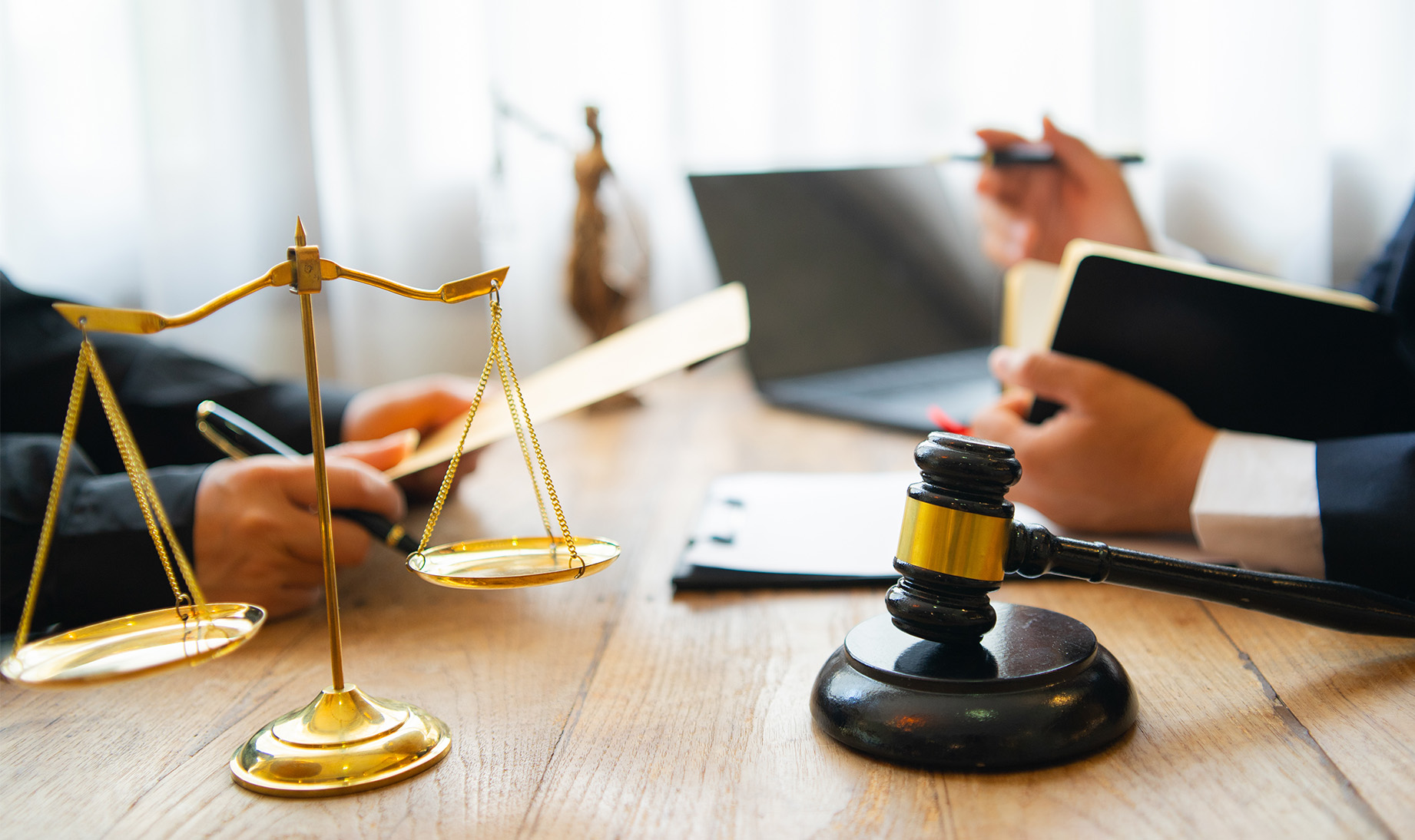 lawyer and client sitting facing each other with scales and gavel on desk